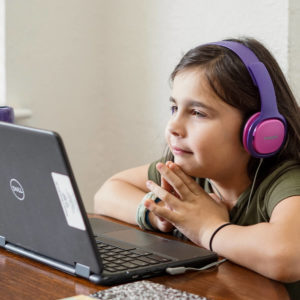 Girl wearing headphones while she watches something on a DELL laptop