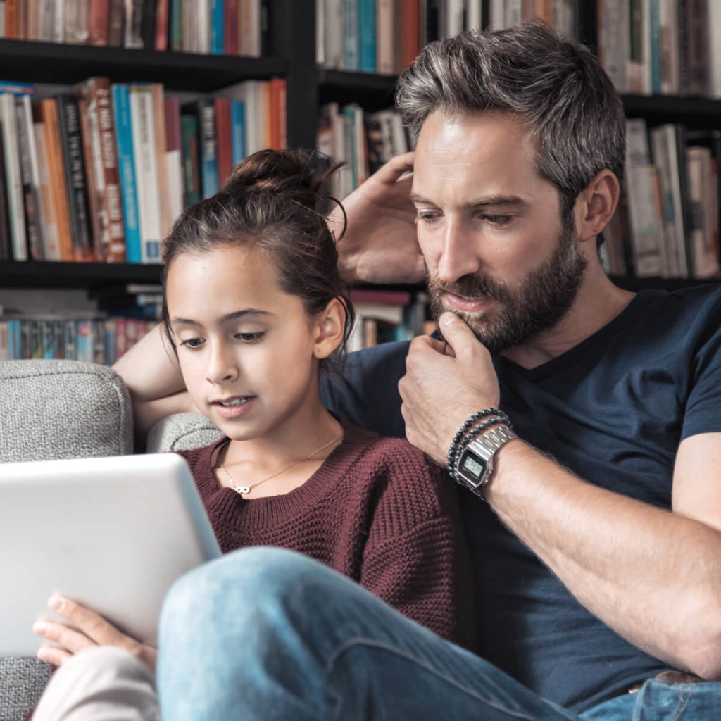 Young girl sitting with dad looking at iPad