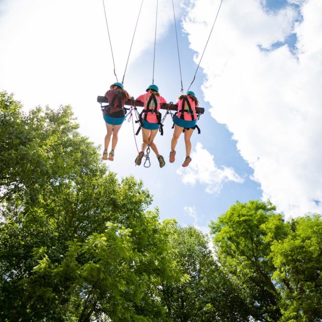 3 girls swing on a high-ropes course at Snowbird Wilderness Outfitters