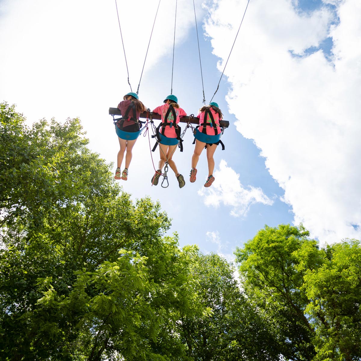 3 girls swing on a high-ropes course at Snowbird Wilderness Outfitters.